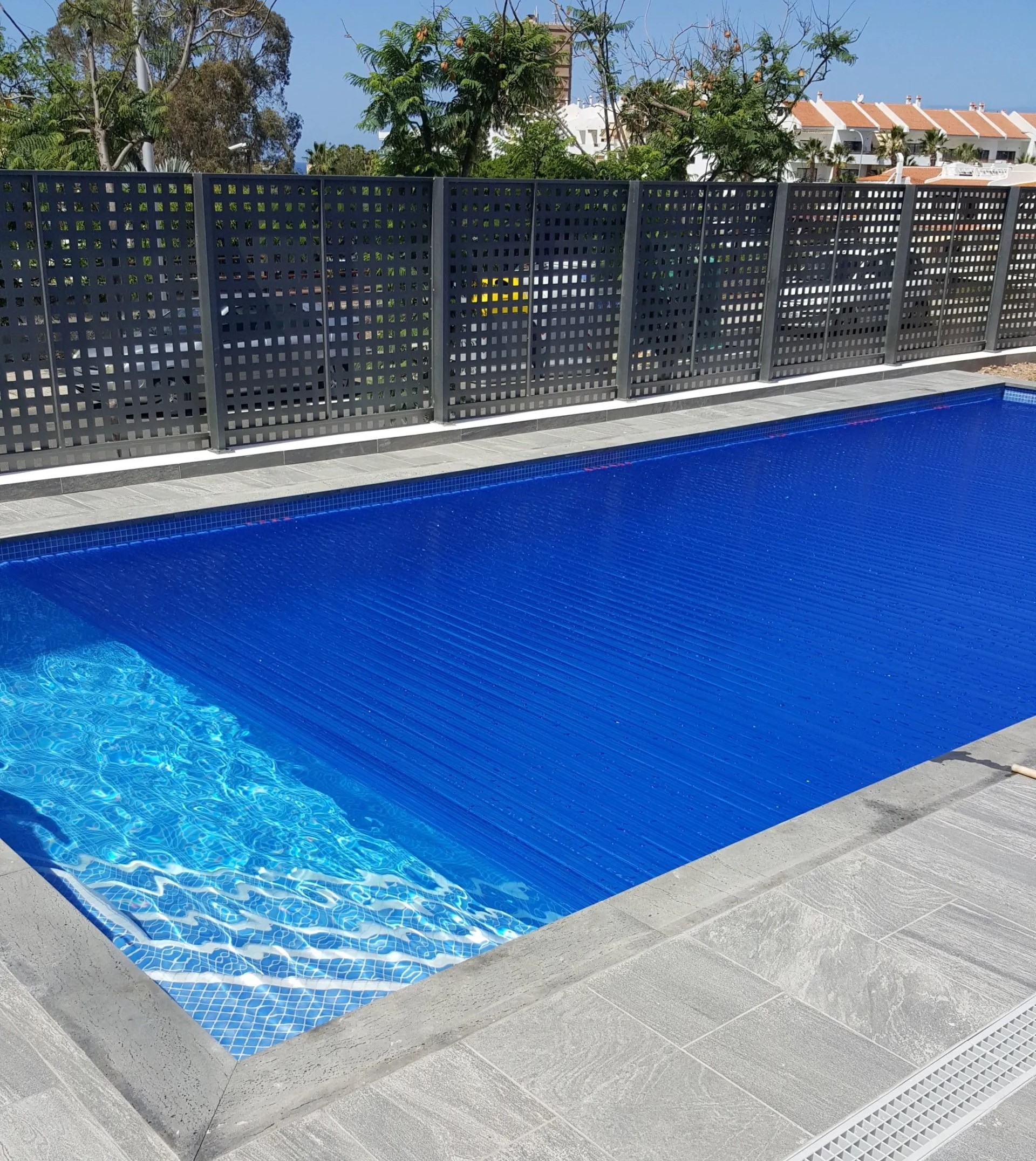 Piscina azul en Tenerife con vistas panorámicas y árboles alrededor